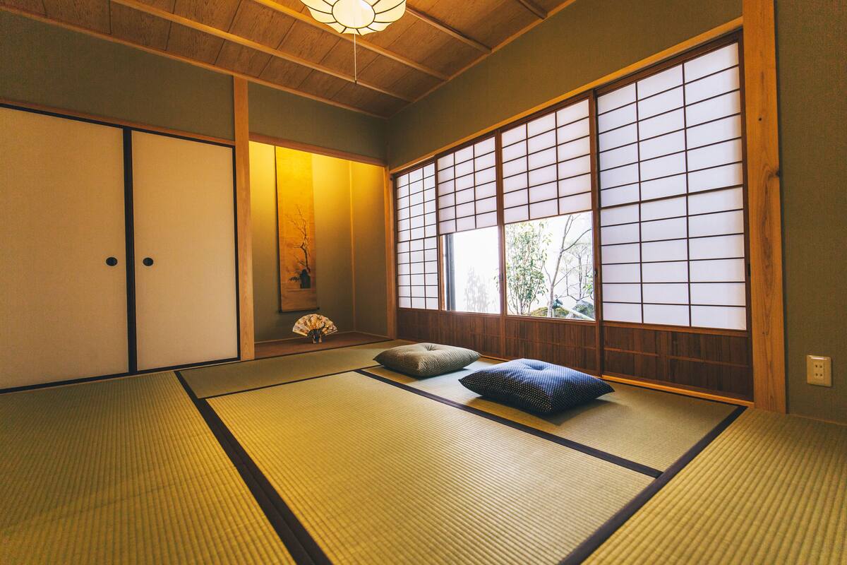 Una habitación tradicional japonesa con suelo de tatami, puertas correderas y vistas a través de pantallas shoji.