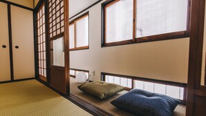 Une pièce de style japonais traditionnel, avec un sol recouvert de tatamis, des paravents en papier de riz (shoji) et un futon avec des oreillers.