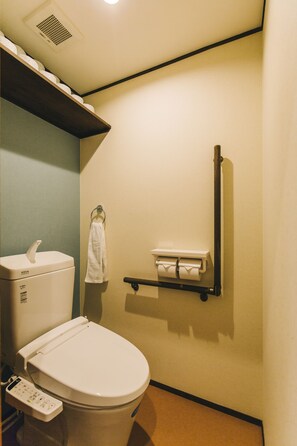 Een moderne badkamer met toilet, handdroger, handdoekhouder en plank met toiletpapier.