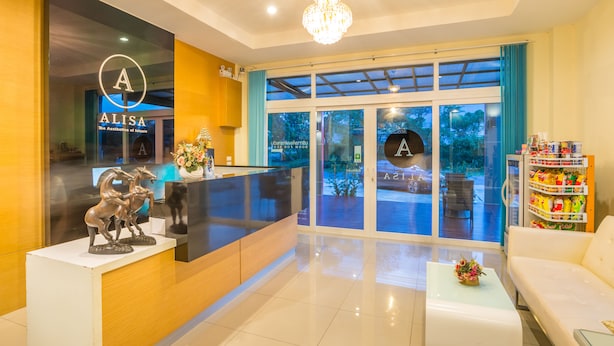 Un área de recepción de diseño moderno, con mostrador de recepción, candelabro y zona de estar con sofá y mesa de centro.