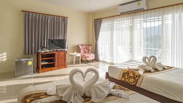 A hotel room with two beds, a TV, a refrigerator, a small table, a chair, and curtains.