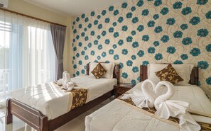 A hotel room with two beds, floral wallpaper, and towels arranged in swans. - Alisa Krabi Hotel (Krabi)