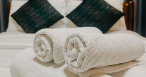 A neatly made bed with white linens and a pillow with a dark green pattern. - Alisa Krabi Hotel (Krabi)