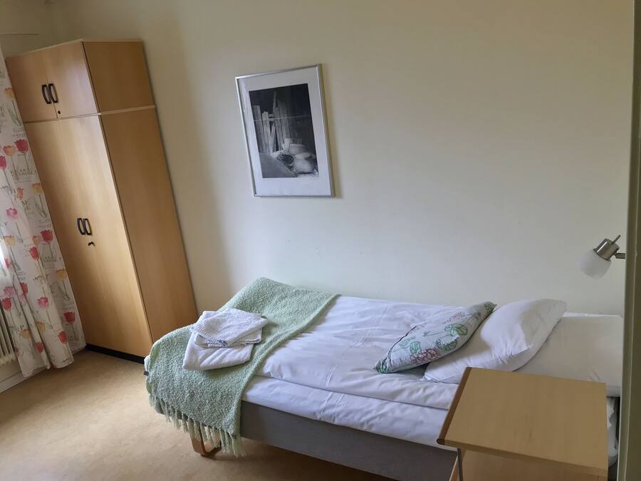 Une chambre à coucher avec un lit, une armoire, un tableau encadré et une table de chevet.
