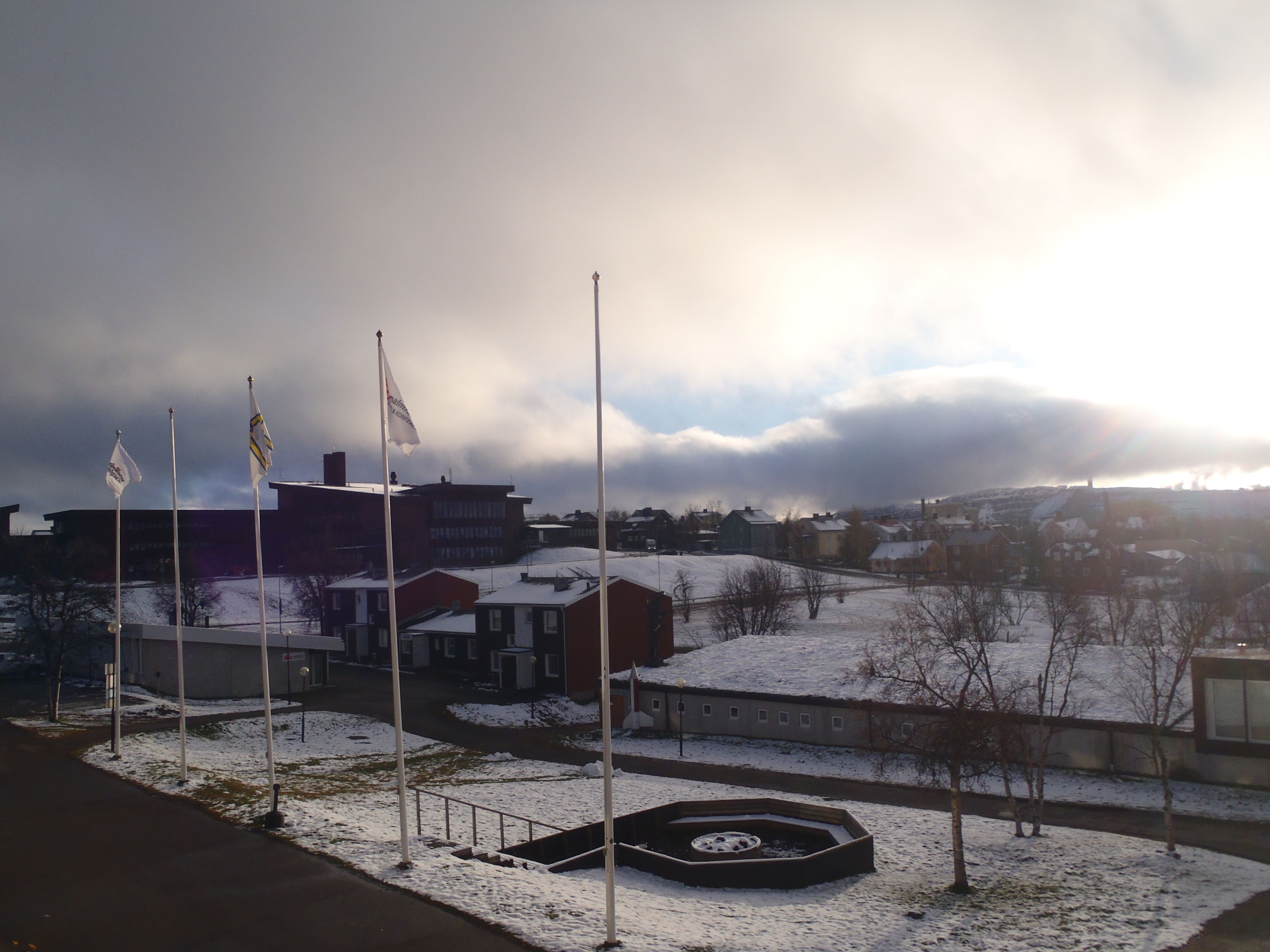 A snowy landscape with buildings, flags, and a circular structure.