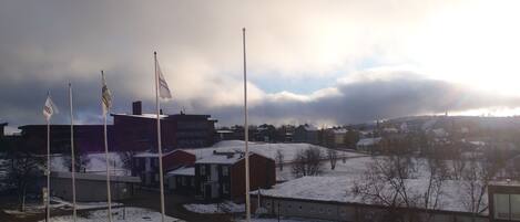 A snowy landscape with buildings, flags, and a circular structure.