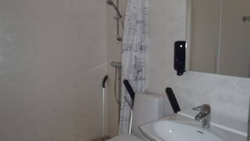 Une salle de bain avec des toilettes, un lavabo et une douche.