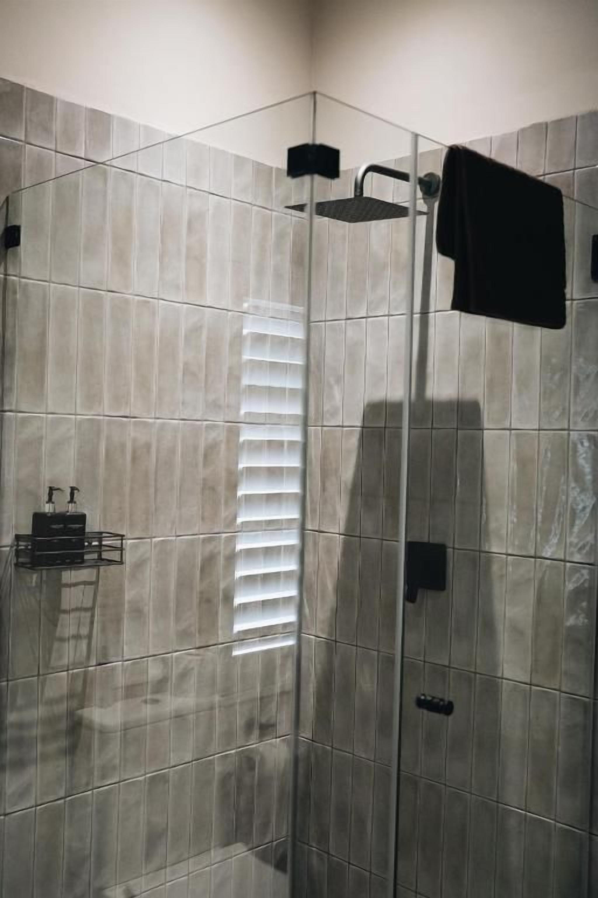 A shower area with a glass enclosure, a towel rack, and a toilet.