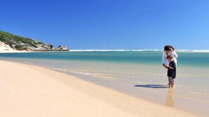 Una spiaggia con acqua cristallina e un promontorio roccioso sullo sfondo.