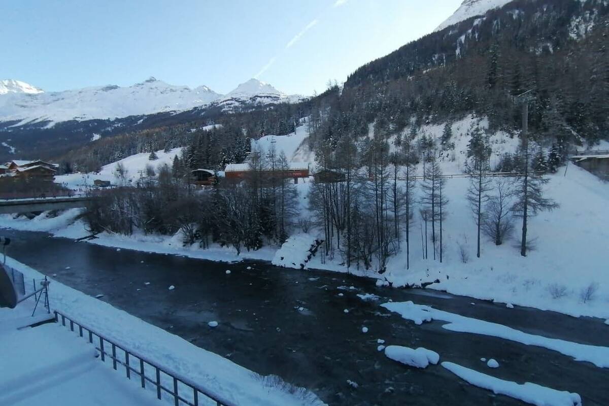 A river flowing through a snowy landscape with mountains in the background.