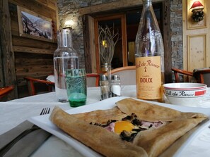 Una mesa de comedor con un crepé, una botella de vino y un bol.