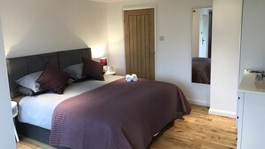 A bedroom with a bed, bedside table, and a mirror. - TOR Rooms (Canterbury)
