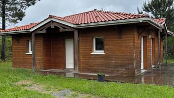 Een houten chalet met een rood dak, een veranda en een klein raam.