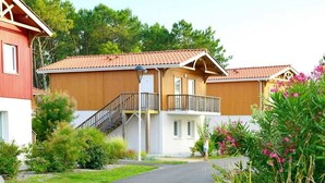Un bâtiment en bois à deux étages, doté d’un balcon, d’un escalier et d’une allée pavée.