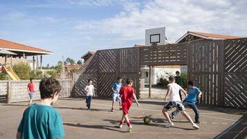 Une aire de jeux avec un panier de basket et une clôture en bois.