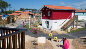 Un bâtiment rouge et blanc, avec un toit rouge, entouré d’une zone recouverte de gravier et agrémenté d’une terrasse en bois au premier plan.