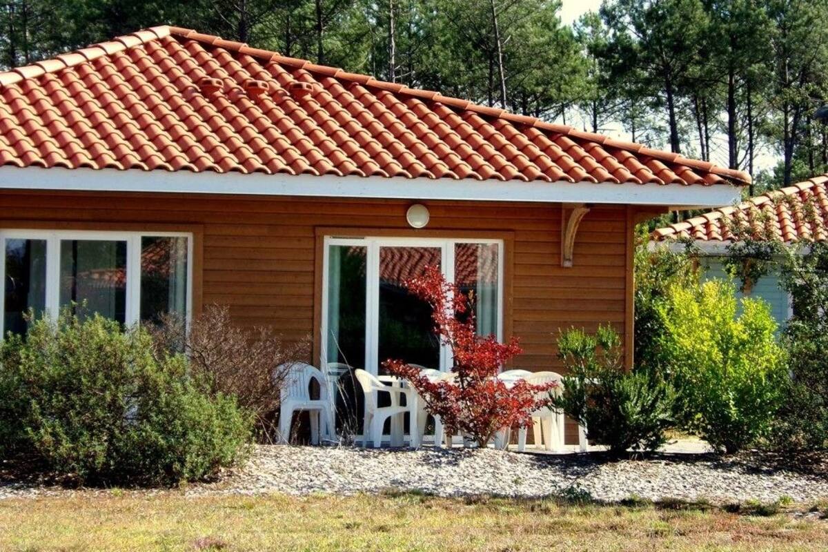 Una casa de fusta amb teulada de rajola, una porta d'entrada i un petit pati amb mobles de jardí.