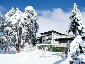 Ein modernes Hotel mit flachem Dach, großen Fenstern und einem Balkon.