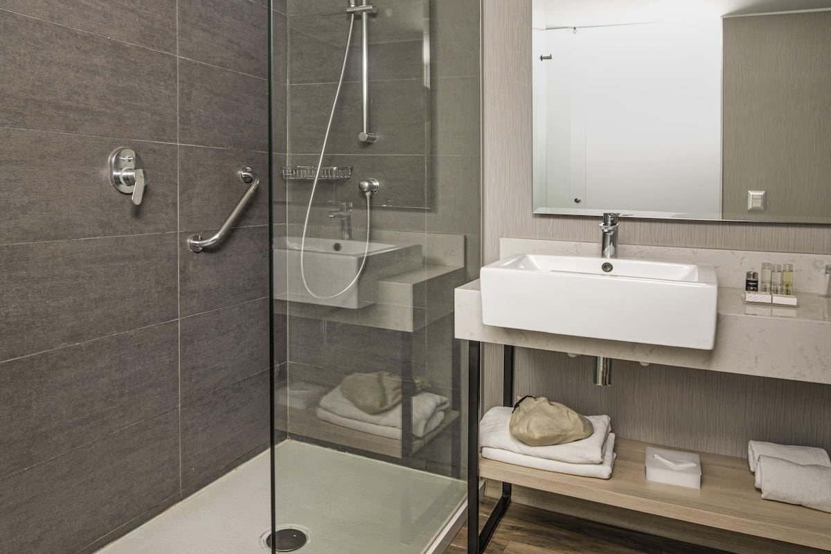 A modern bathroom with a glass-enclosed shower, a sink, and a mirror.