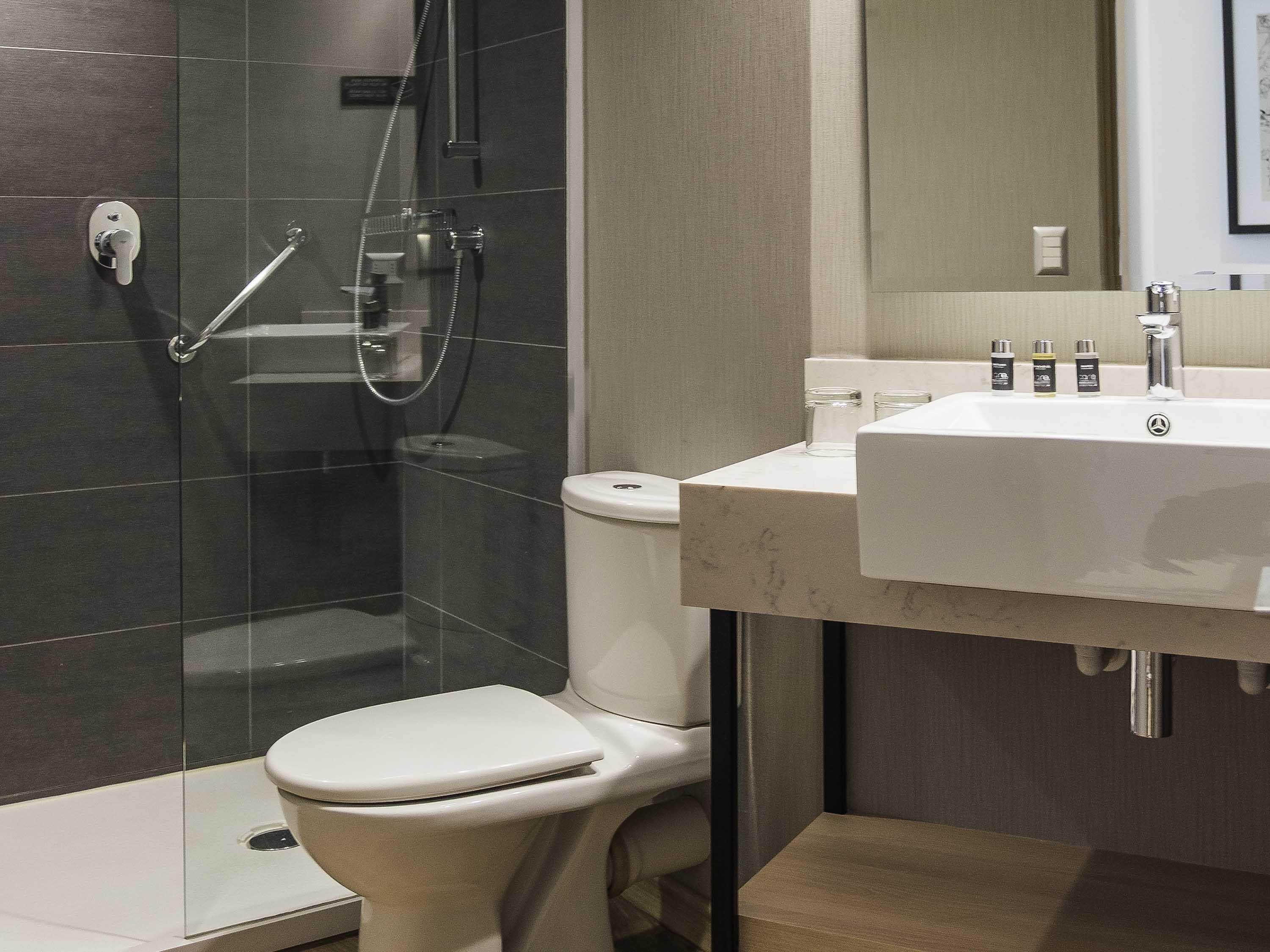 A modern bathroom with a glass-enclosed shower, a white toilet, and a sink with toiletries.