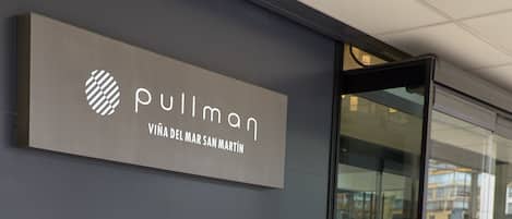 Une femme est en train de faire ses lacets devant un bâtiment sur lequel on peut lire l’inscription « Pullman ».