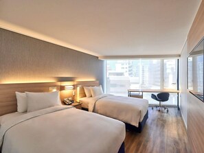 A hotel room with two beds, a desk, and a chair.