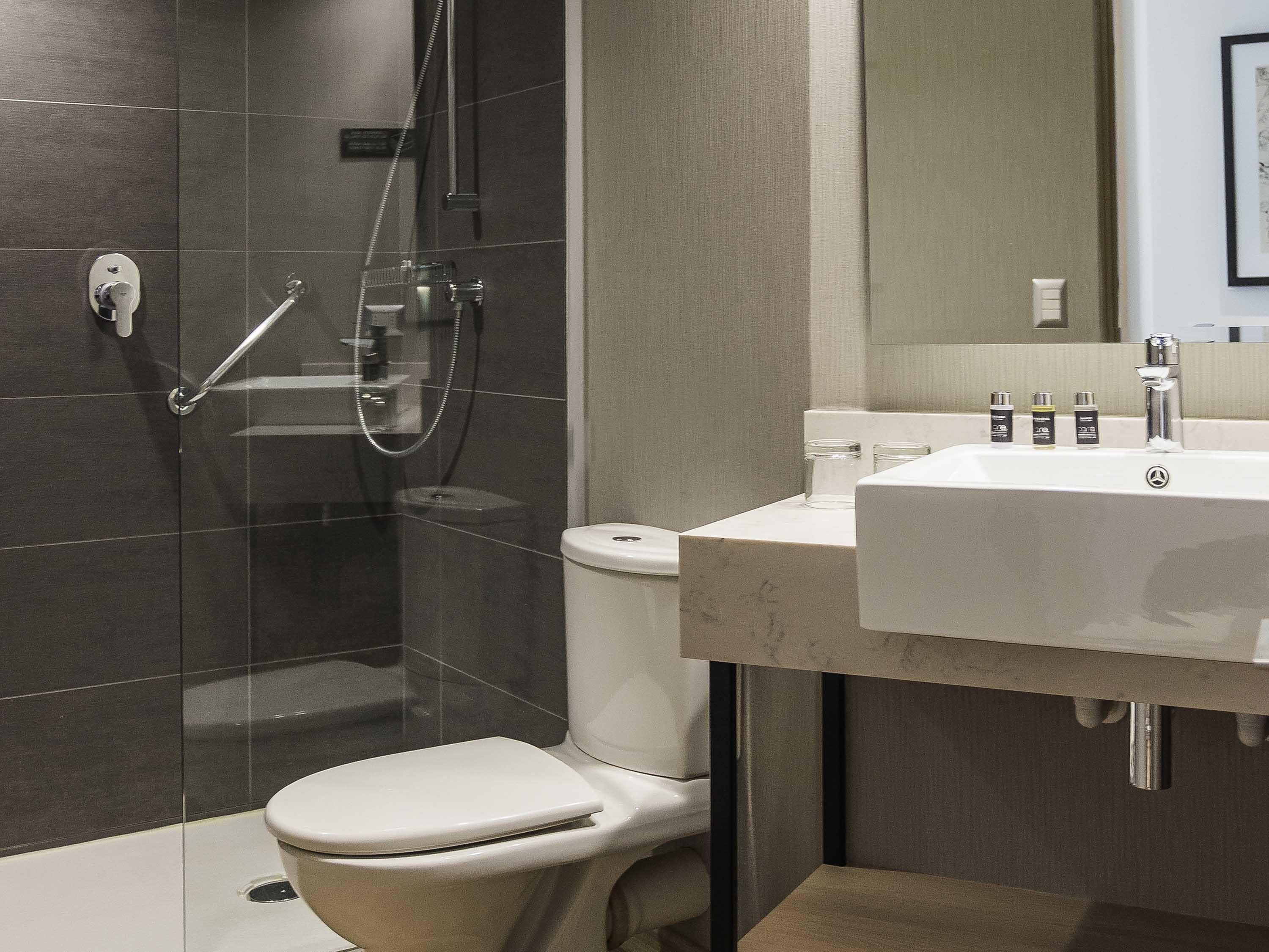 A modern bathroom with a glass-enclosed shower, a toilet, and a sink with toiletries.