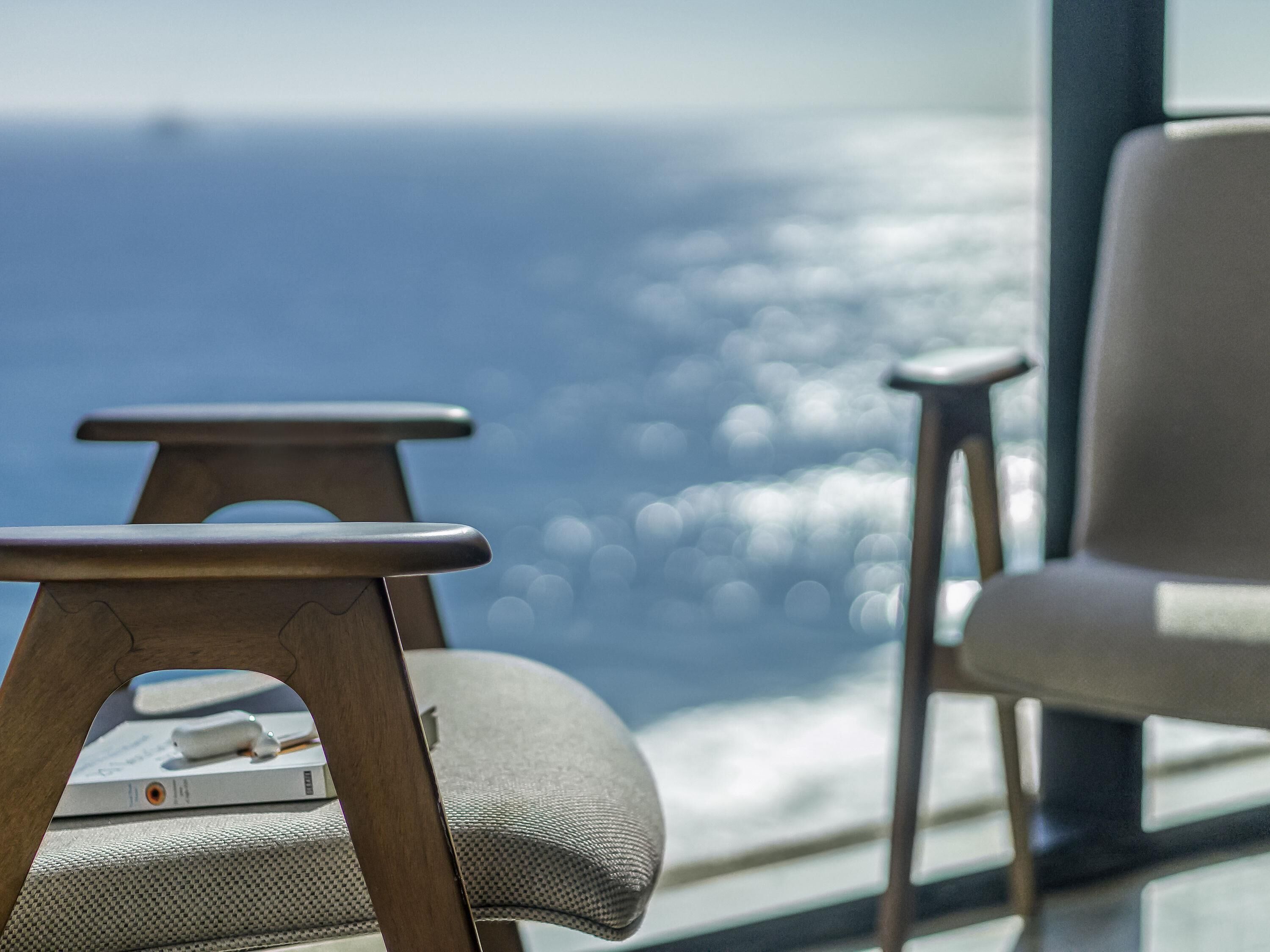 Una habitación moderna con vista al océano, que cuenta con un sofá y una pequeña mesa de madera.