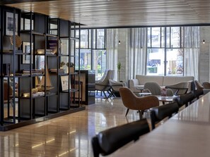 Un intérieur moderne avec une longue table, des sièges et une bibliothèque contenant divers objets.