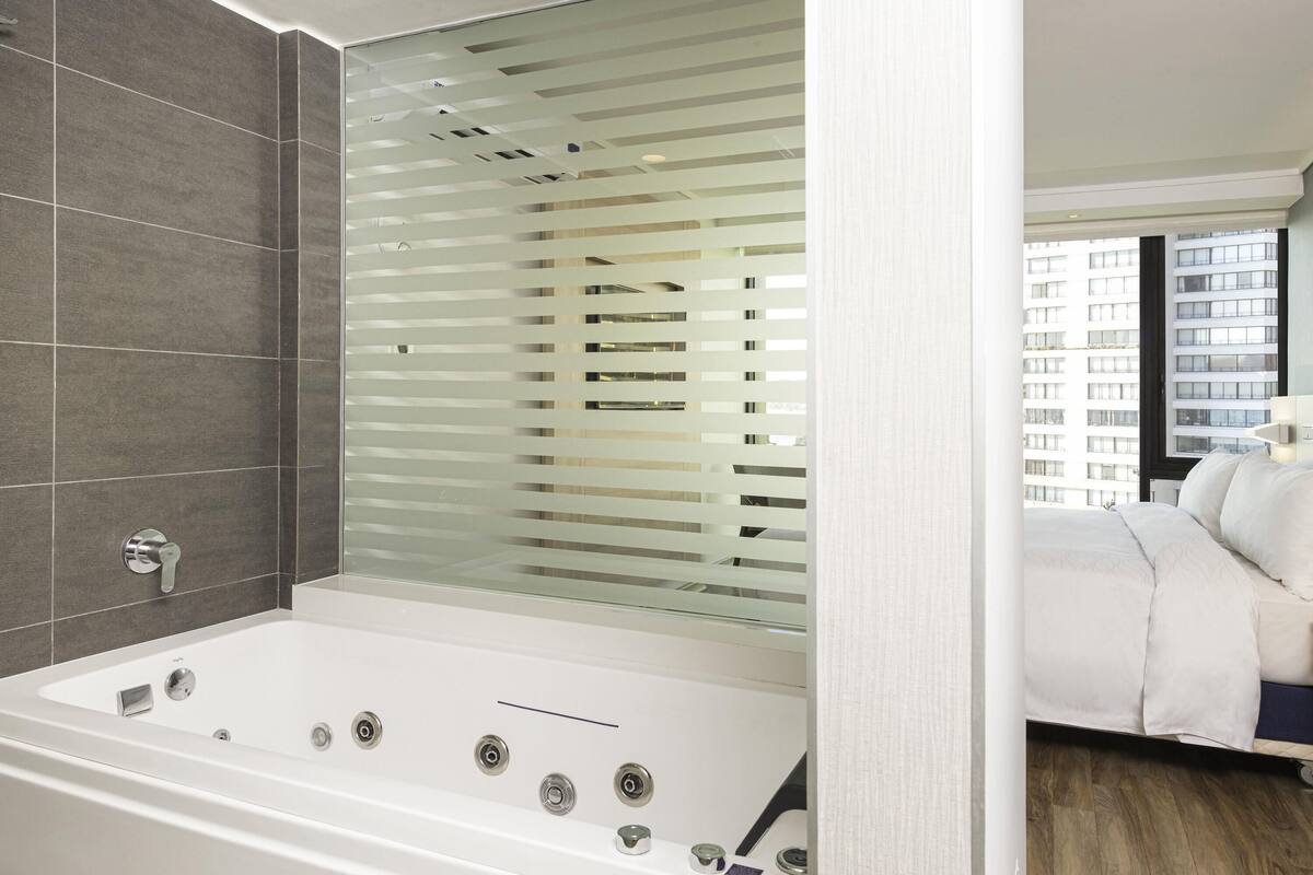 A modern bathroom with a large bathtub, a shower area, and a glass partition.