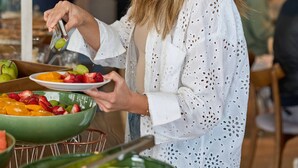 Una persona se sirve de un bufé con diversas frutas y verduras.