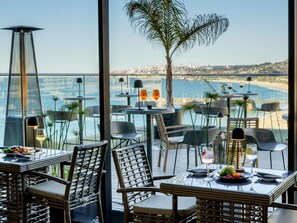 A restaurant with outdoor seating overlooking a beach and cityscape. - Pullman Viña del Mar San Martín (Vina del Mar)