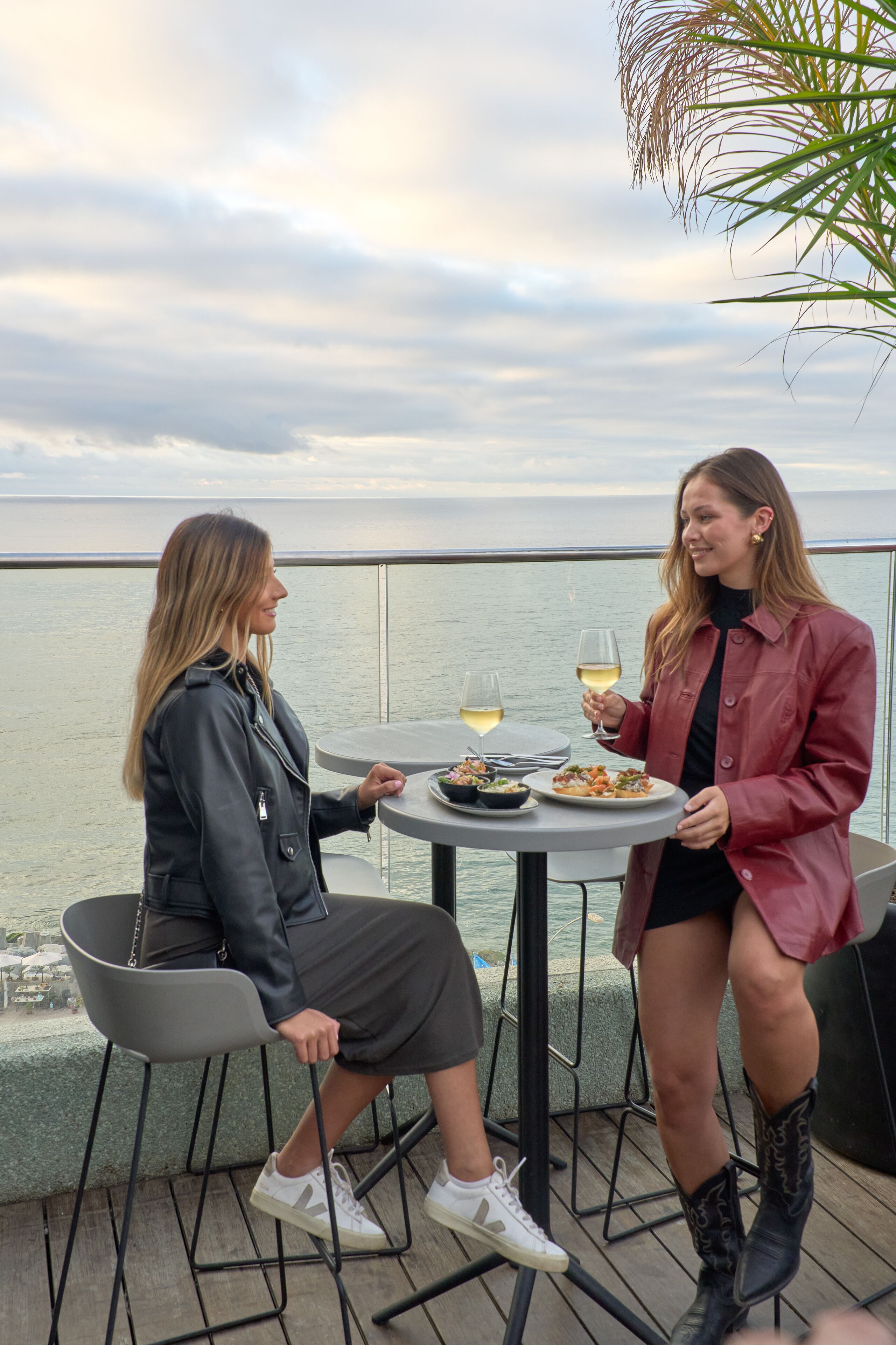 Two people dining at an outdoor table with a view of the sea.