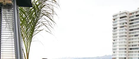 Dos personas sentadas en una mesa en un balcón con vista a una playa y un puente.
