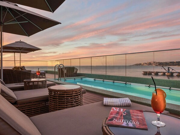 A poolside area with lounge chairs, a glass table, and a magazine. - Pullman Viña del Mar San Martín (Vina del Mar)