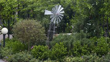 A windmill surrounded by lush greenery and a lamp post.