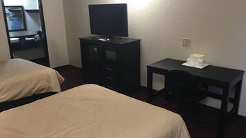 Ein Hotelzimmer mit zwei Betten, einem Schreibtisch, einem Stuhl, einem Fernseher und einem kleinen Tisch mit einer Taschentuchbox.