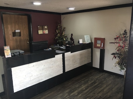 A reception desk with a white and black design, a wooden door, and a bulletin board with notices.