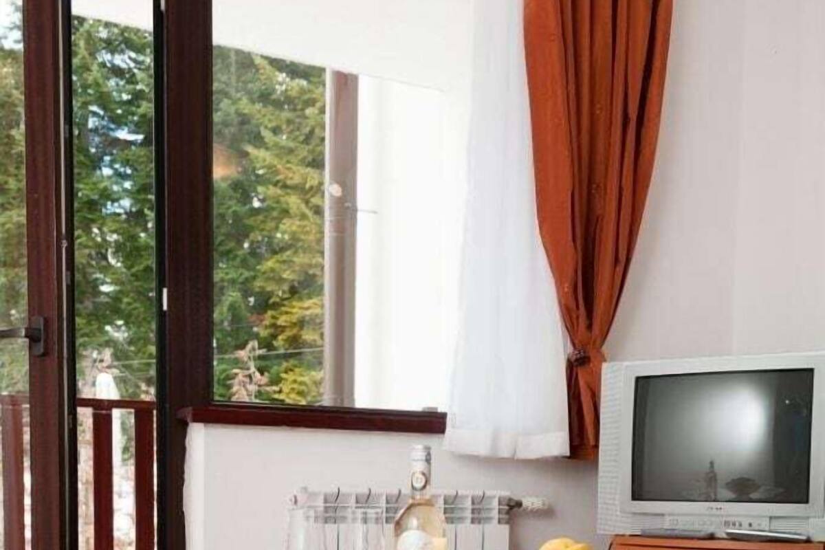 Una habitación moderna con una mesa de vidrio, un frutero y un televisor.