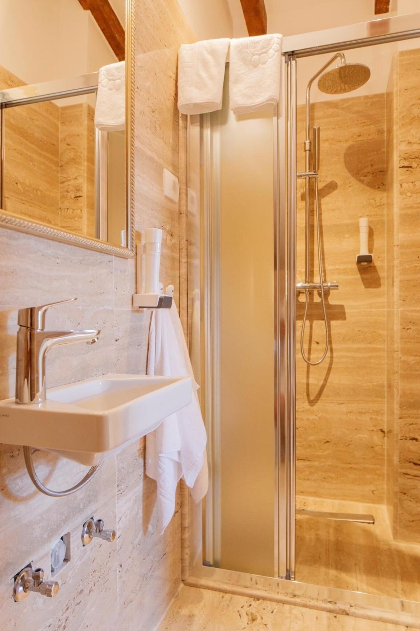 A modern bathroom with a glass-enclosed shower, a white sink, and a mirror.
