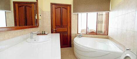 Un baño con lavamanos doble, bañera y espejo.