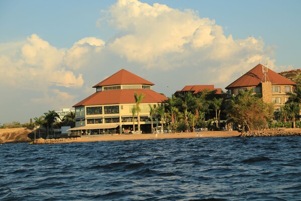 A beachfront hotel with multiple buildings, a swimming pool, and a view of the ocean.