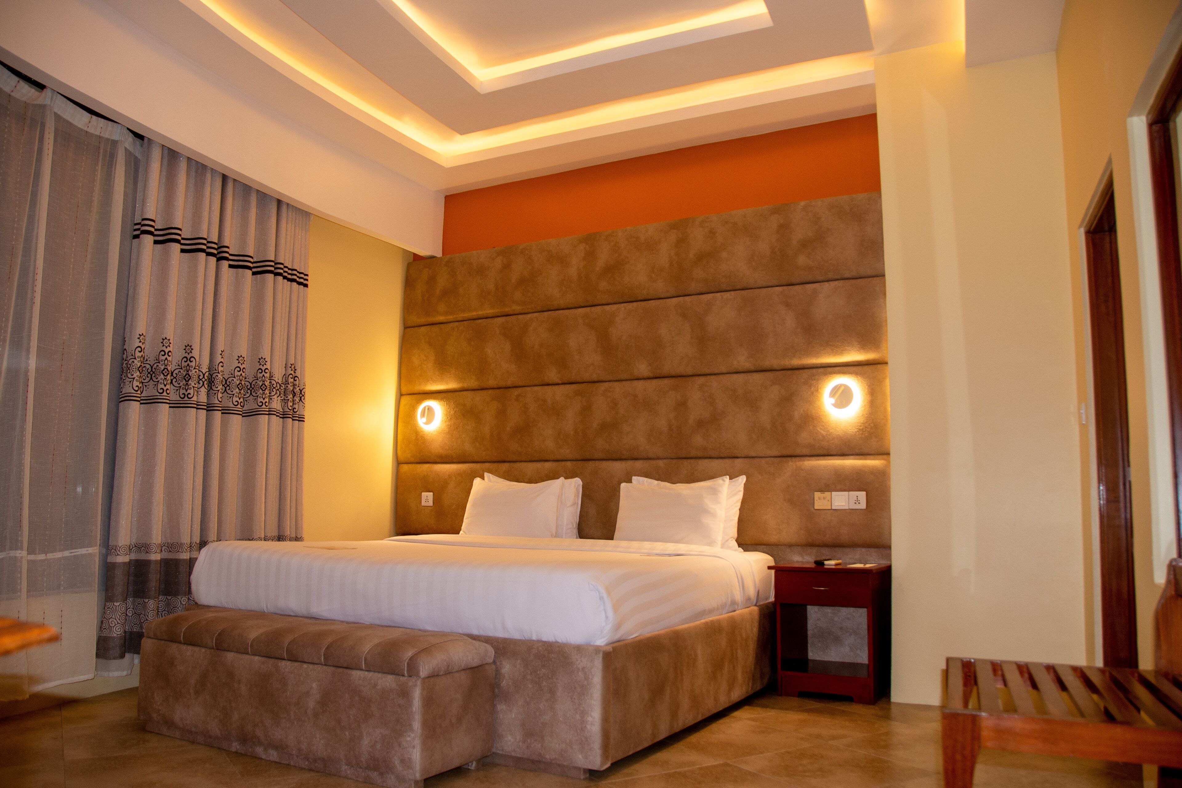 Un dormitorio moderno con una cama grande, un banco y una mesita de noche.