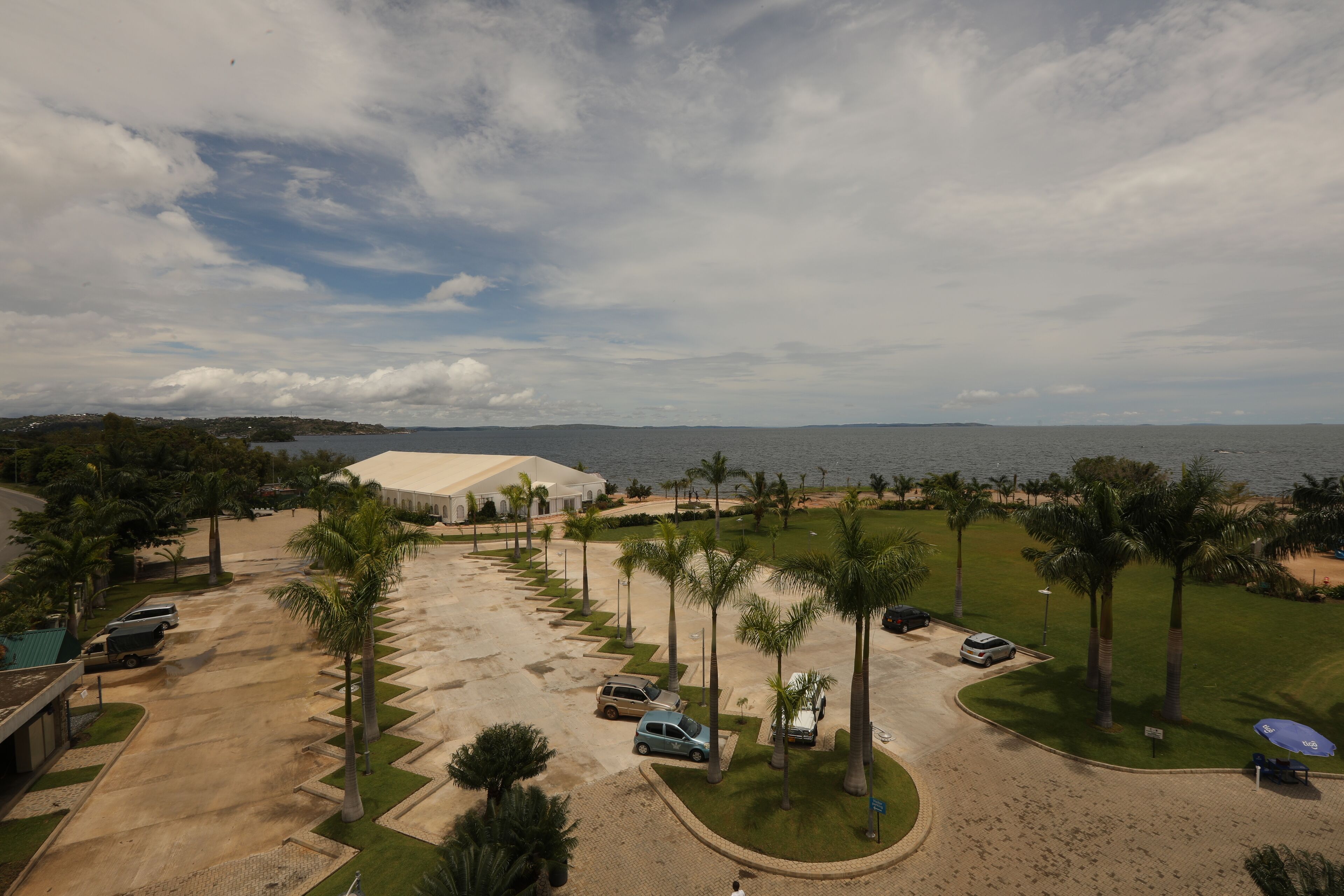Un hôtel situé sur la côte, doté d’un parking, de palmiers et offrant une vue sur la mer.