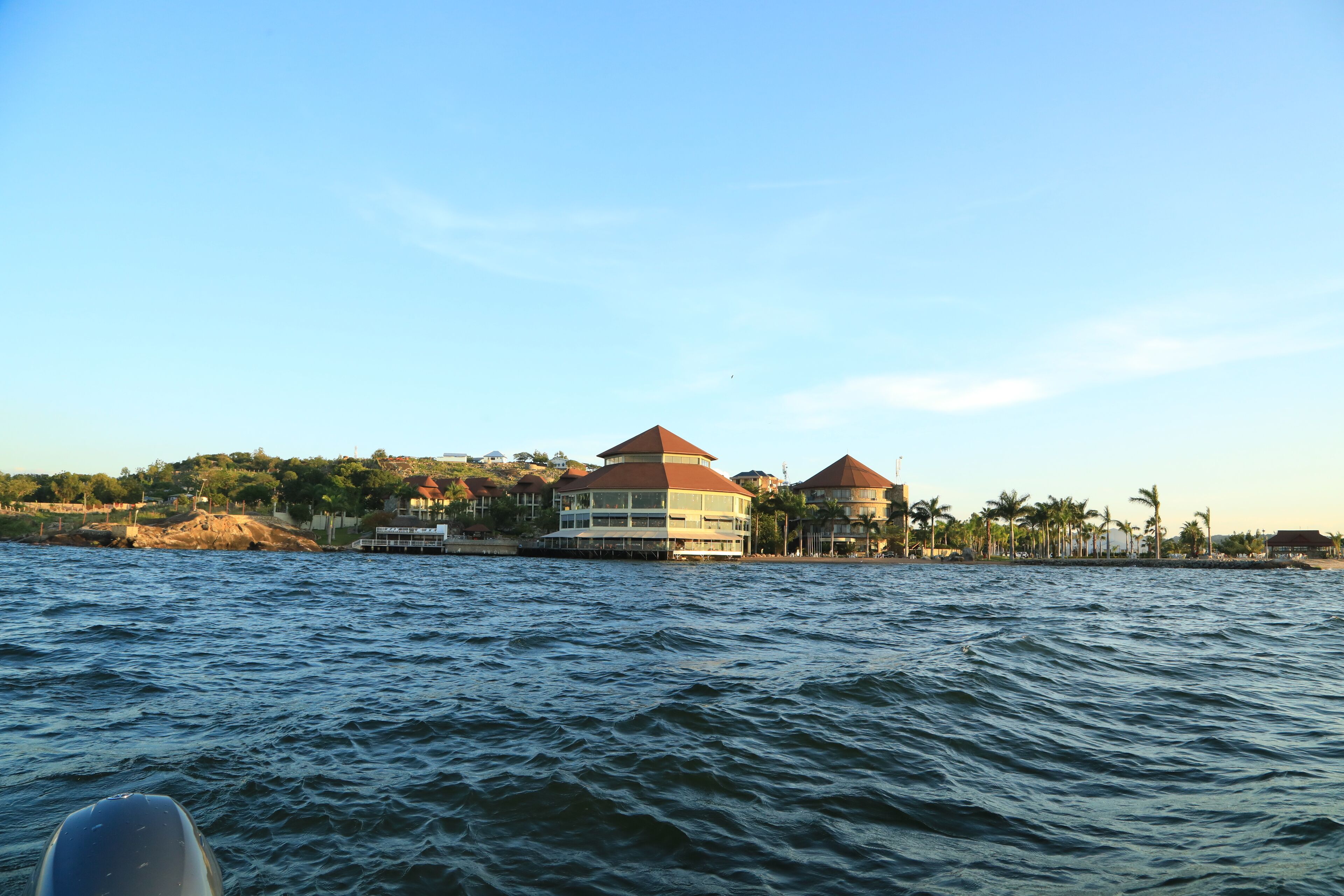 A waterfront hotel with multiple buildings, a dock, and palm trees.