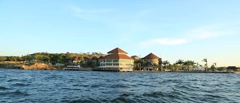 A waterfront hotel with multiple buildings, a dock, and palm trees.