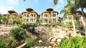 A resort with multiple buildings featuring balconies, a waterfall, and a rocky landscape with greenery. - Malaika Beach Resort (Mwanza)