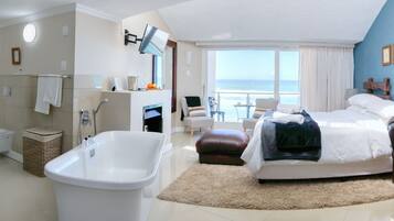 Ein modernes Hotelzimmer mit einem großen Bett, einer Sitzecke, einem Badezimmer mit Badewanne und Meerblick.