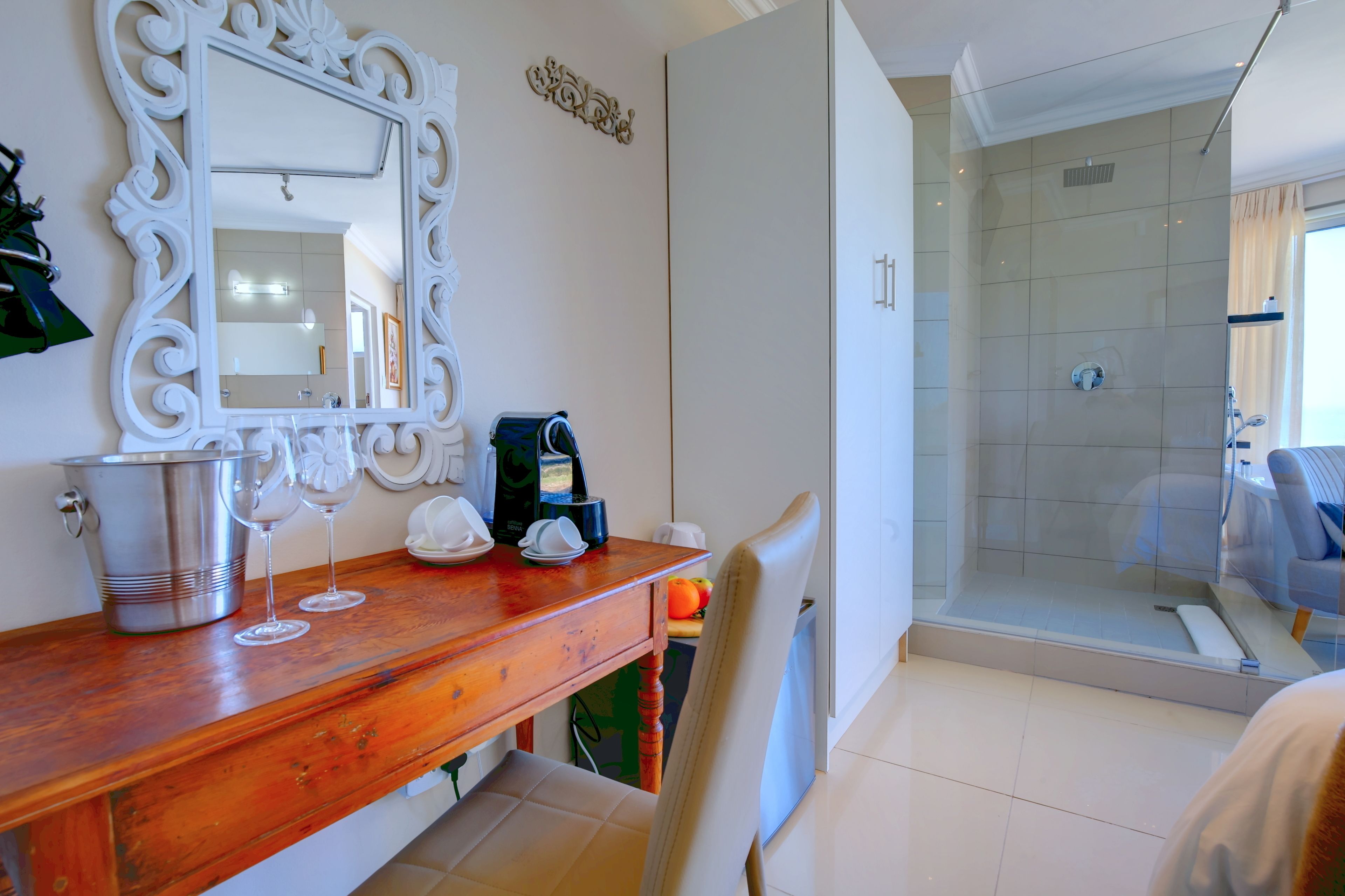 A bathroom with a wooden vanity, a large mirror, a shower area, and a white tiled floor.