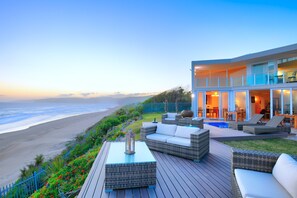 Una propiedad frente a la playa con terraza, mobiliario exterior y piscina.